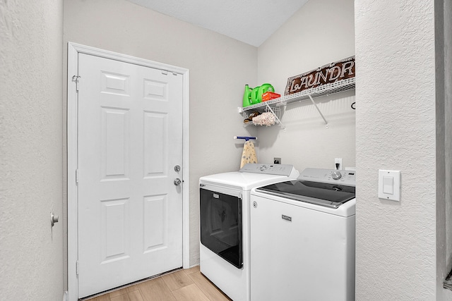 laundry area with laundry area, washer and dryer, light wood-type flooring, and a textured wall