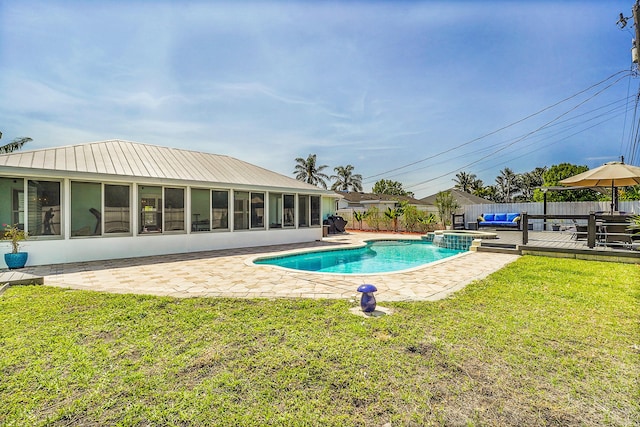 view of pool featuring a pool with connected hot tub, a patio, a fenced backyard, a yard, and a sunroom