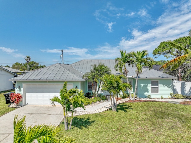 ranch-style house featuring an attached garage, metal roof, a front yard, and concrete driveway