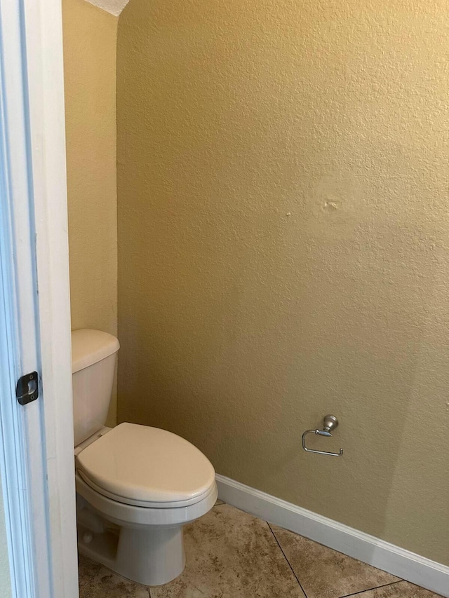 bathroom featuring baseboards, toilet, and tile patterned flooring