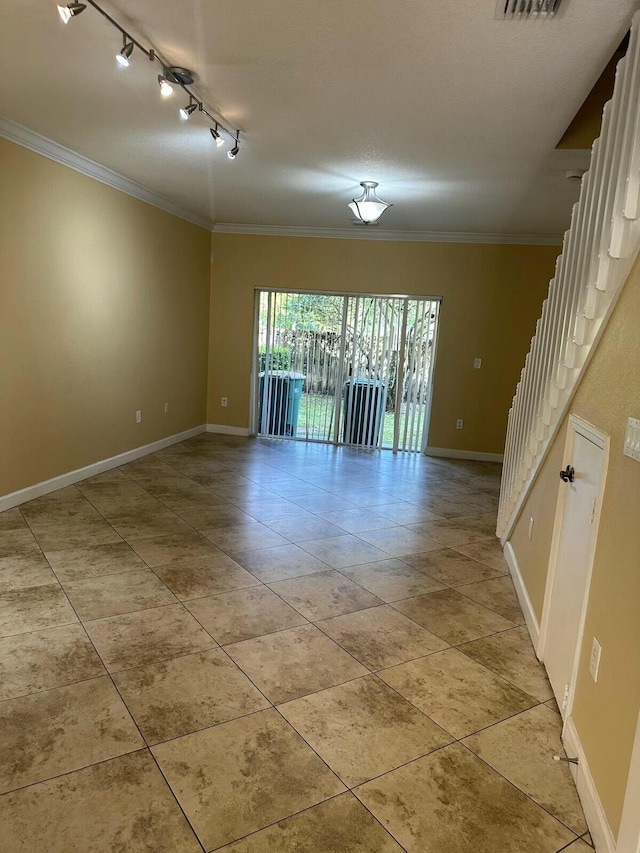 spare room featuring light tile patterned floors, baseboards, visible vents, ornamental molding, and rail lighting