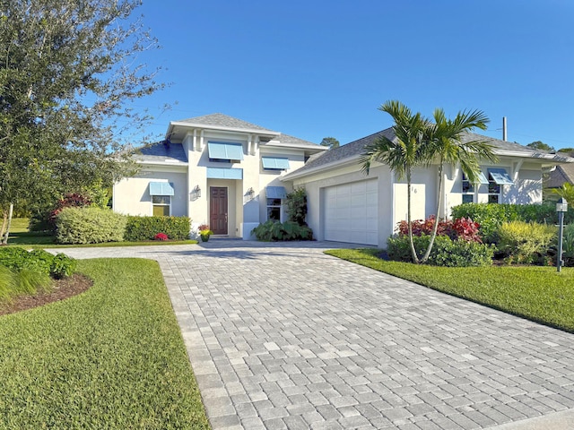 view of front of home featuring a front yard, decorative driveway, a garage, and stucco siding