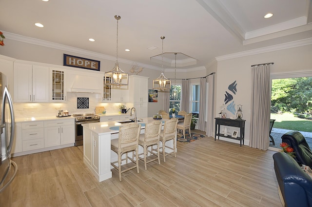 kitchen featuring a breakfast bar, custom exhaust hood, a wealth of natural light, and appliances with stainless steel finishes