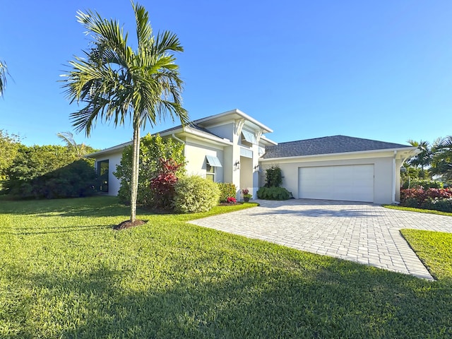 view of front of property featuring stucco siding, decorative driveway, a front lawn, and an attached garage