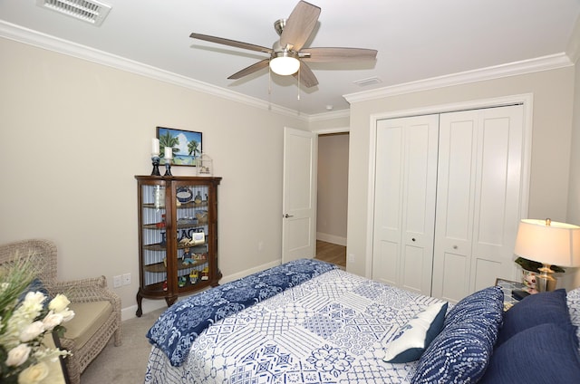 carpeted bedroom with crown molding, baseboards, visible vents, and a closet