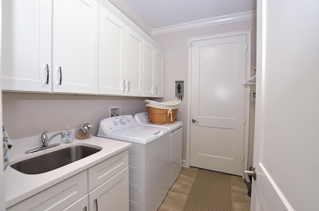 clothes washing area featuring washer and clothes dryer, a sink, cabinet space, light wood-style floors, and crown molding