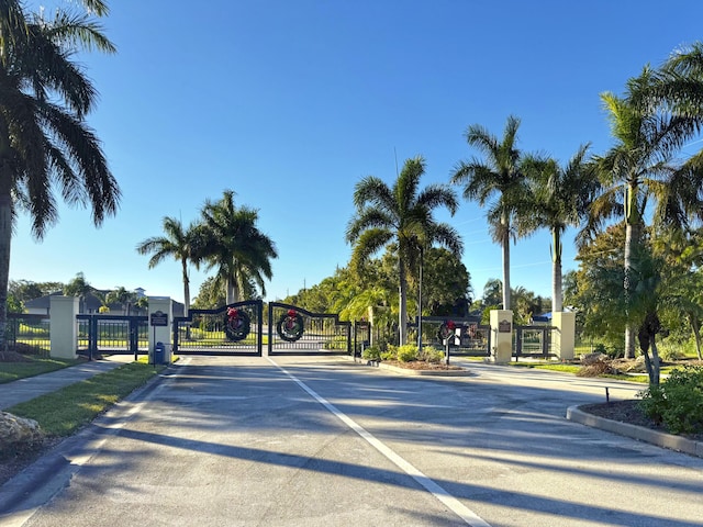 view of street featuring a gate, curbs, sidewalks, and a gated entry