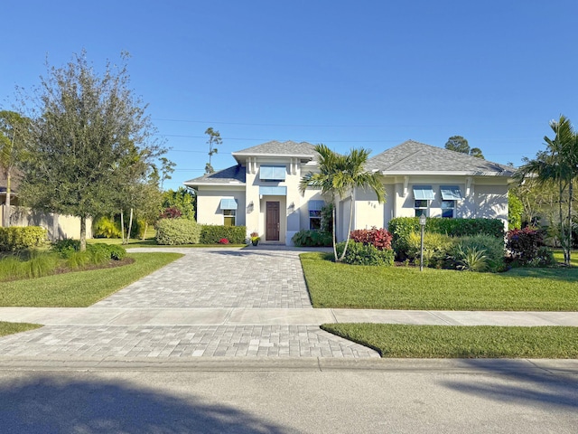 view of front of home with stucco siding, decorative driveway, and a front yard