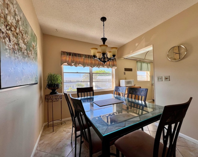 dining space featuring a notable chandelier, light tile patterned flooring, baseboards, and a textured ceiling