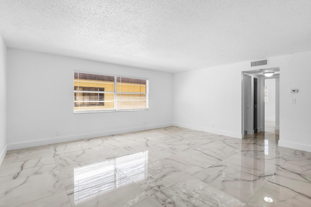 unfurnished room featuring visible vents, baseboards, a textured ceiling, and marble finish floor