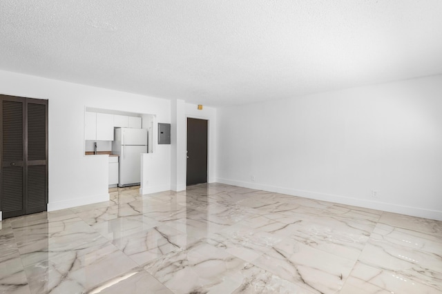 unfurnished room with electric panel, marble finish floor, a textured ceiling, and baseboards