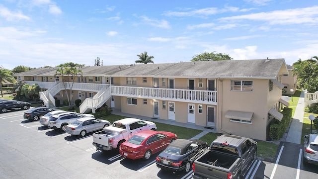 view of building exterior featuring stairs, uncovered parking, and a residential view