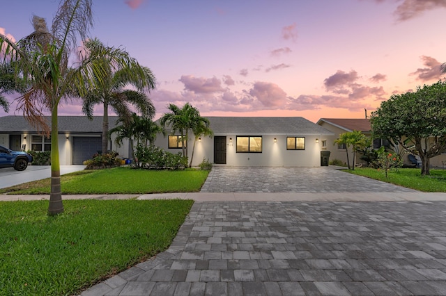 view of front of property featuring a shingled roof, stucco siding, a front lawn, and decorative driveway
