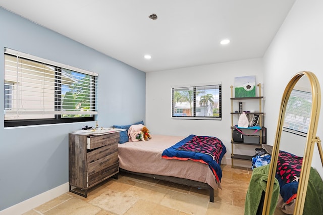 bedroom with recessed lighting, stone tile floors, and multiple windows