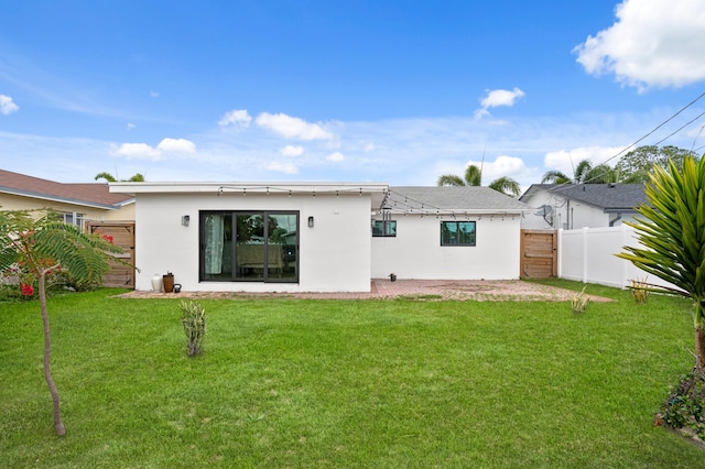 back of house featuring stucco siding, fence, and a lawn