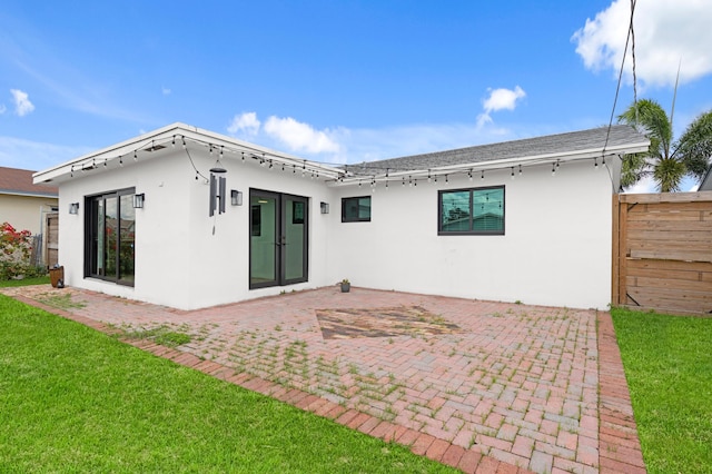 back of property with a yard, stucco siding, roof with shingles, a patio area, and fence