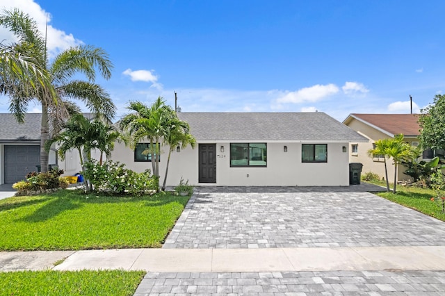 ranch-style home featuring stucco siding, a front yard, and decorative driveway