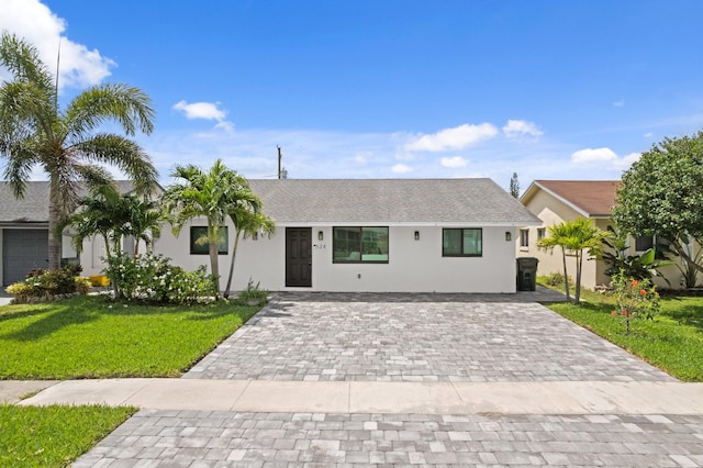 single story home with stucco siding, a front yard, and decorative driveway