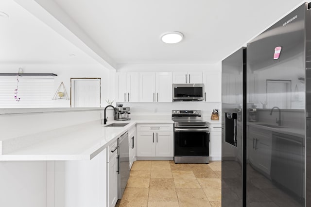 kitchen with stainless steel appliances, light countertops, white cabinetry, and a sink