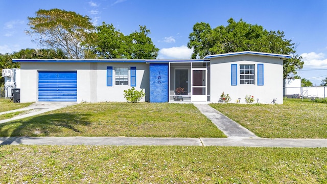 view of front of property featuring a garage, stucco siding, a front lawn, and a sunroom