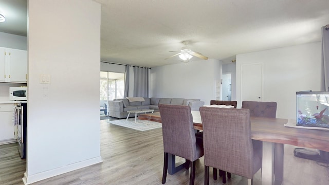 dining area with light wood-style flooring and ceiling fan