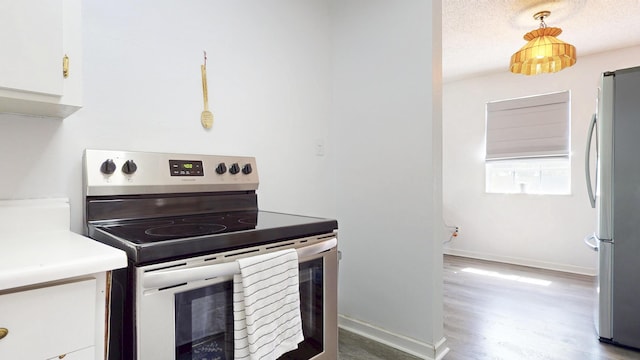 kitchen featuring baseboards, appliances with stainless steel finishes, wood finished floors, a textured ceiling, and white cabinetry