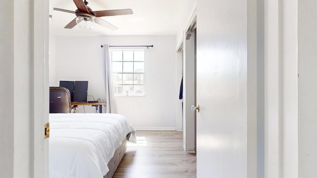 bedroom with ceiling fan, baseboards, and wood finished floors