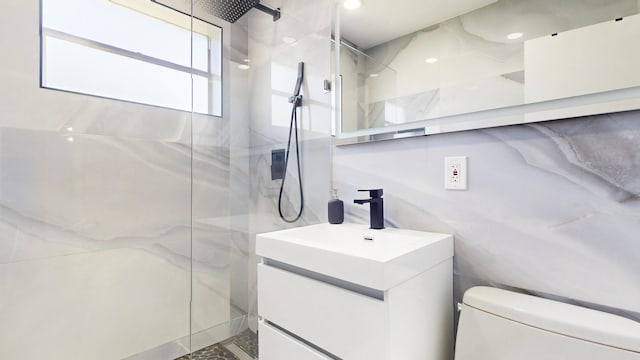 bathroom with a marble finish shower, toilet, tile walls, and vanity