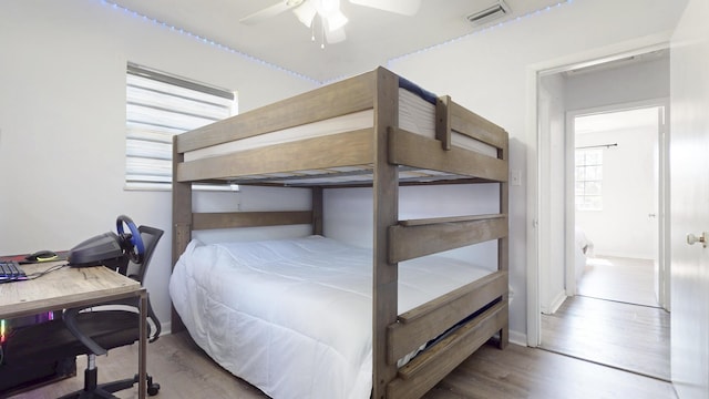 bedroom with ceiling fan, wood finished floors, visible vents, and baseboards