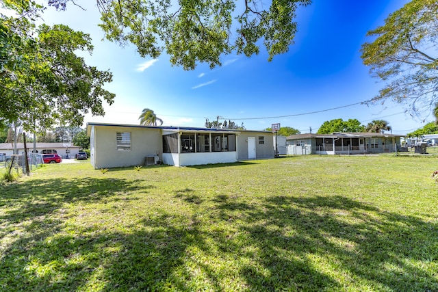 back of property featuring central air condition unit, a lawn, fence, and a sunroom