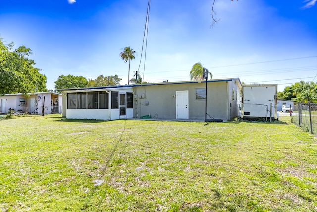 back of property with a gate, a yard, fence, and a sunroom