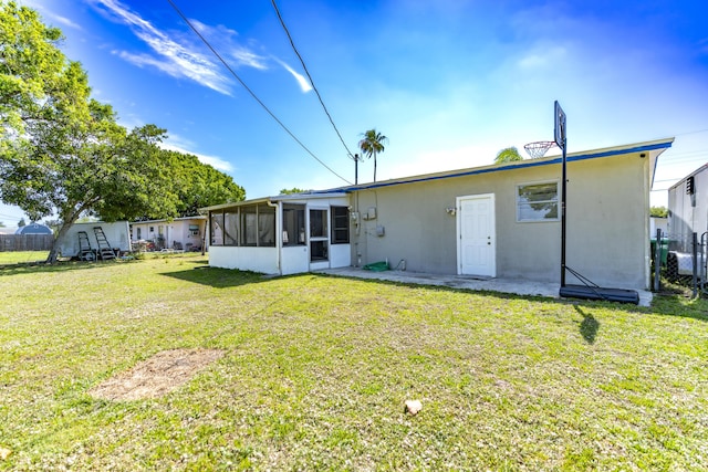 rear view of house with a lawn, fence, a sunroom, and stucco siding