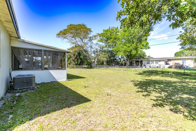 view of yard featuring central air condition unit, a sunroom, and fence