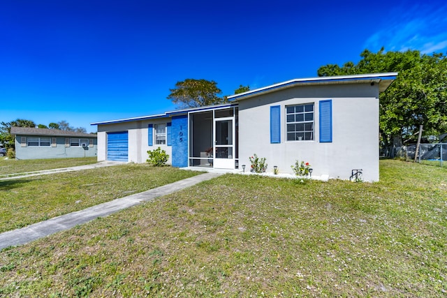 view of front of home with stucco siding, concrete driveway, a front yard, a sunroom, and a garage