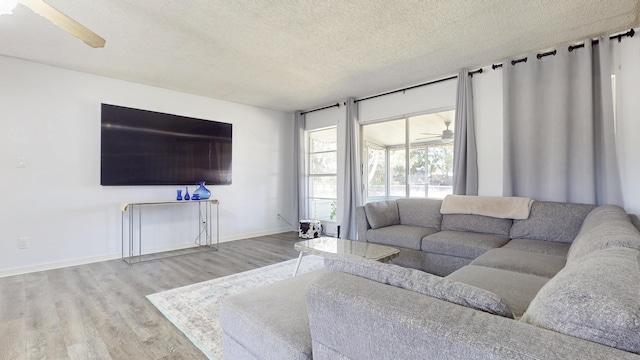 living room with a textured ceiling, wood finished floors, baseboards, and ceiling fan