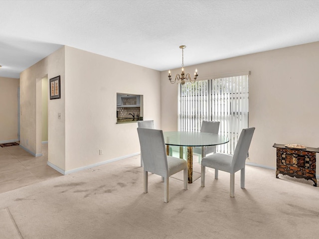 dining area featuring a textured ceiling, an inviting chandelier, baseboards, and light carpet