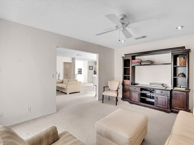 carpeted living room featuring a textured ceiling, baseboards, visible vents, and ceiling fan