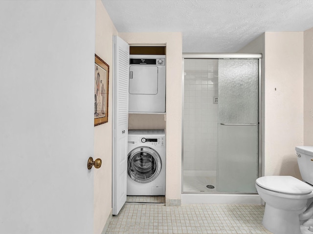 full bathroom with toilet, a stall shower, stacked washing maching and dryer, and a textured ceiling