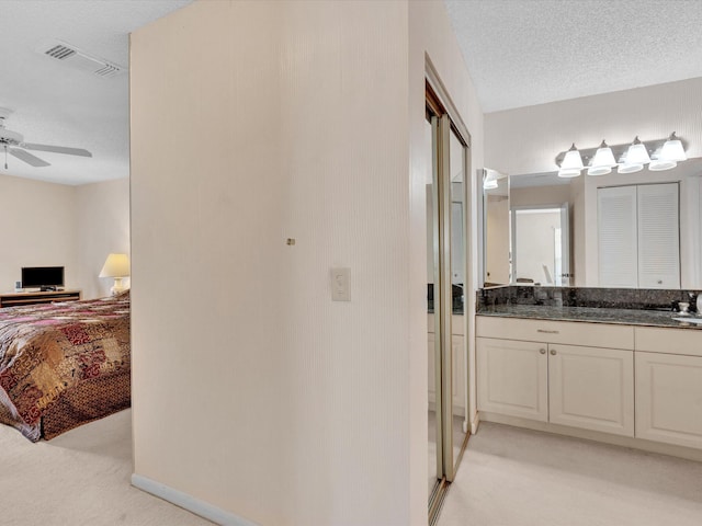 bathroom featuring visible vents, connected bathroom, vanity, a textured ceiling, and a ceiling fan