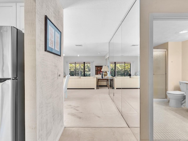 corridor with visible vents, light colored carpet, and baseboards