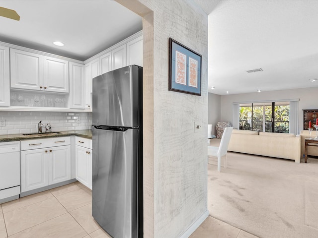 kitchen featuring visible vents, a sink, freestanding refrigerator, white cabinets, and white dishwasher