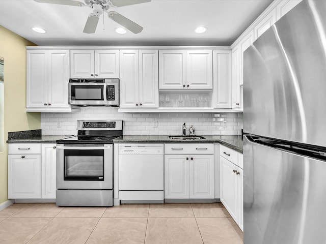 kitchen featuring tasteful backsplash, appliances with stainless steel finishes, light tile patterned flooring, white cabinets, and a sink