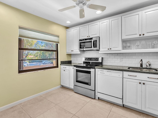 kitchen with light tile patterned floors, a sink, white cabinets, appliances with stainless steel finishes, and backsplash