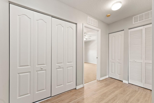 unfurnished bedroom with visible vents, multiple closets, and light wood-style flooring