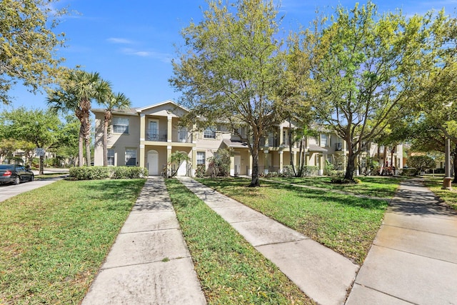 view of property featuring a front yard, a balcony, a residential view, and stucco siding