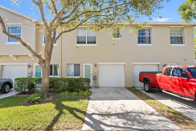 view of property with stucco siding, driveway, and an attached garage