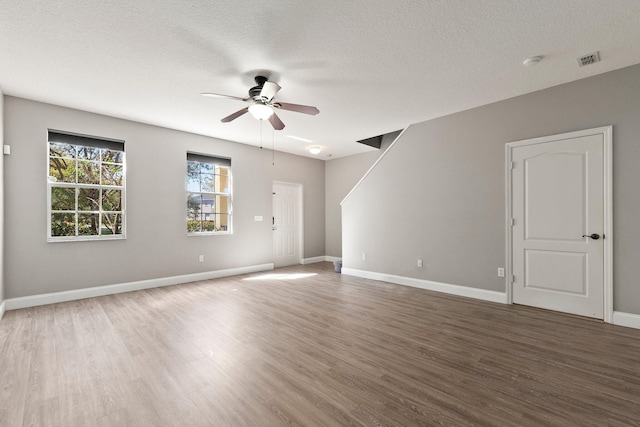 empty room with ceiling fan, baseboards, a textured ceiling, and wood finished floors