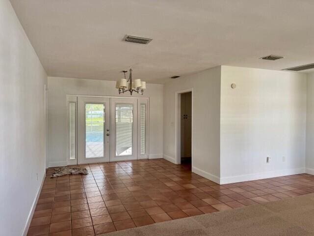 unfurnished room featuring tile patterned floors, visible vents, a chandelier, and french doors