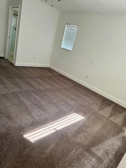 empty room featuring dark carpet and baseboards