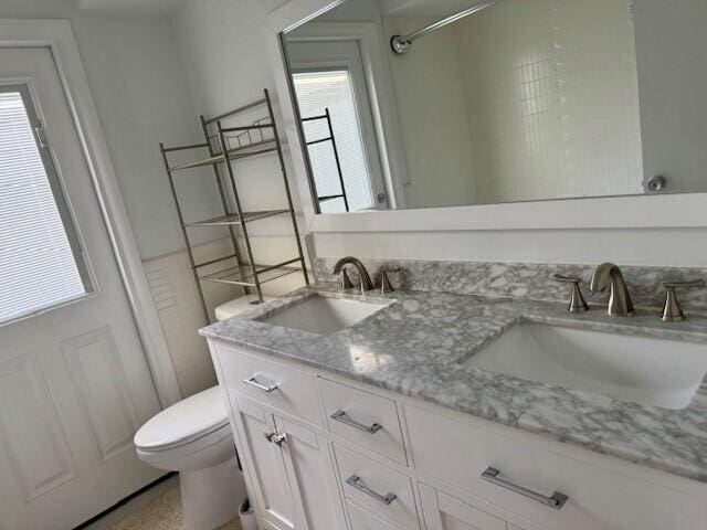 bathroom with double vanity, toilet, and a sink